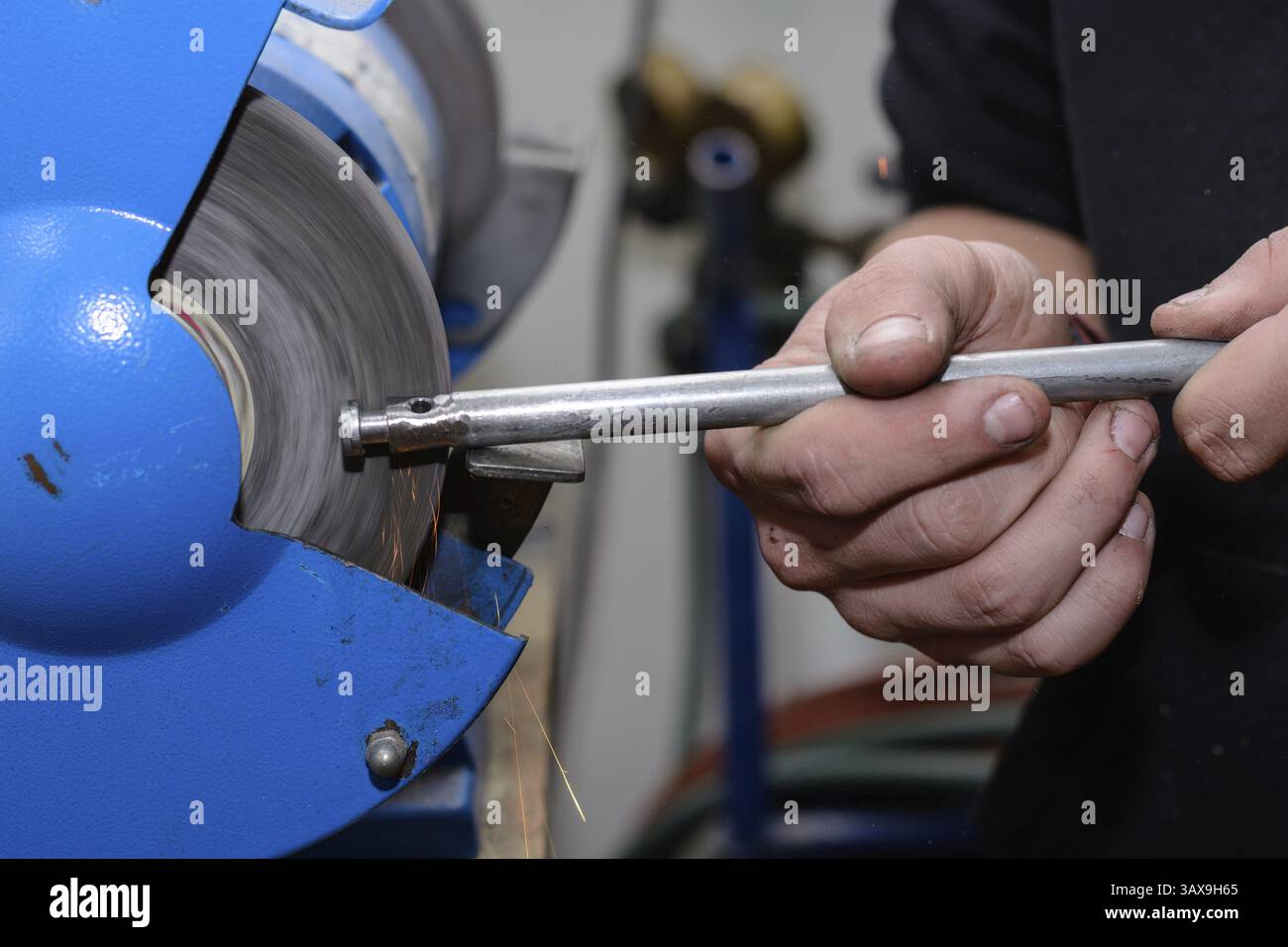 Lavoratore qualificato che lavora su metallo su una smerigliatrice da banco - primo piano Foto Stock
