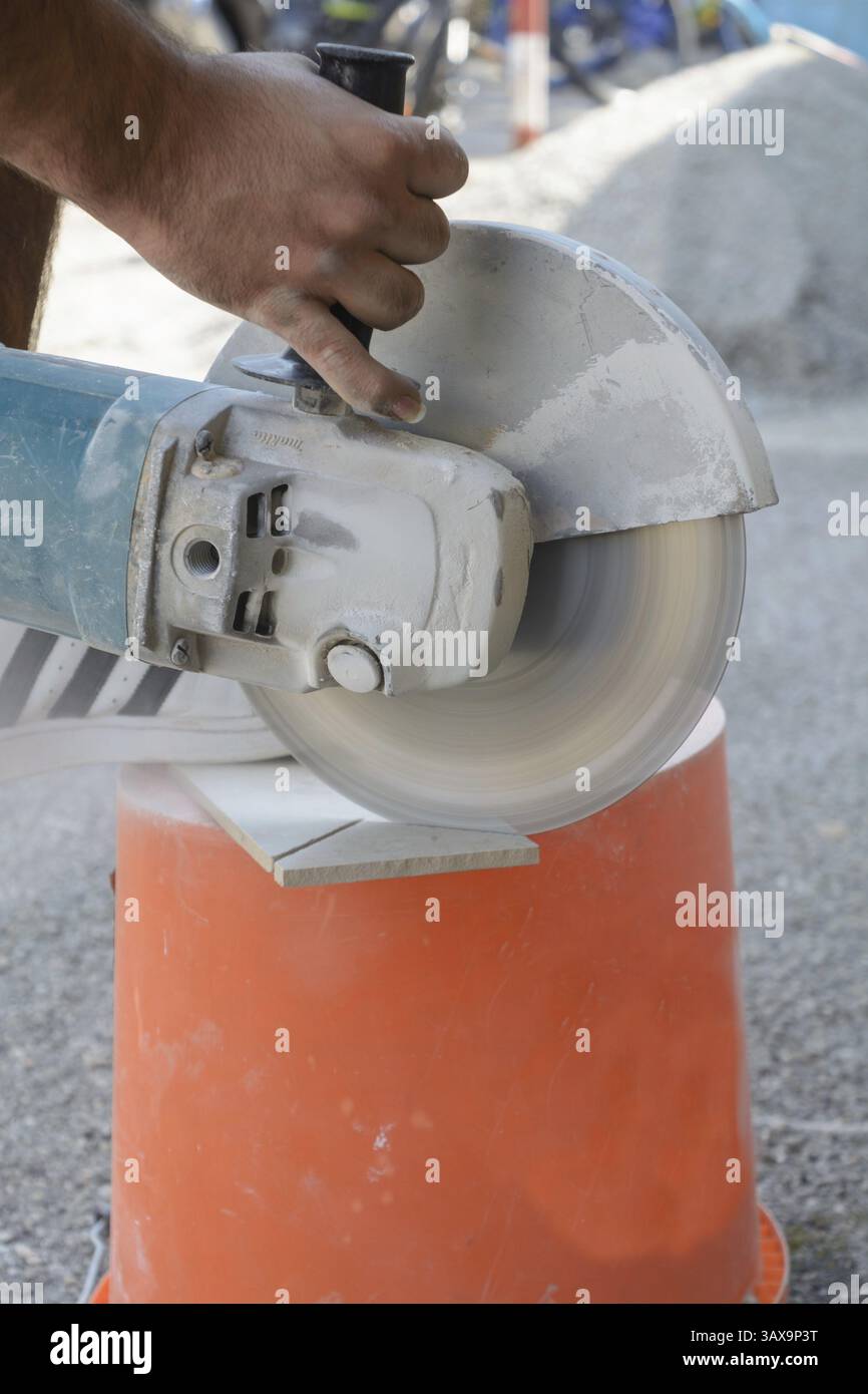 Lavoratore esperto taglia piastrelle con smerigliatrice angolare Foto Stock
