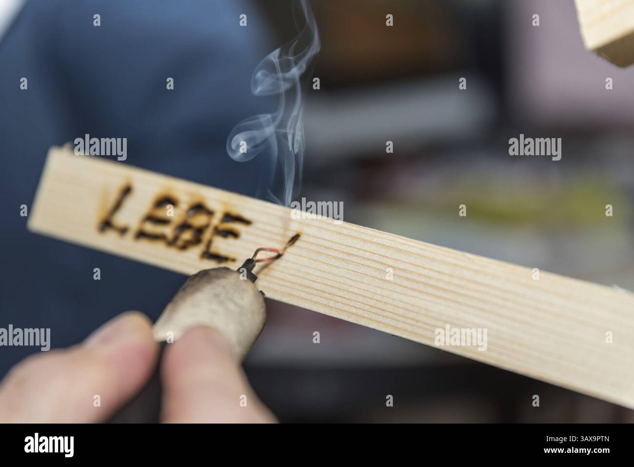 Uno slogan viene creato come un dipinto di fuoco in legno utilizzando un ferro per marchiatura Foto Stock