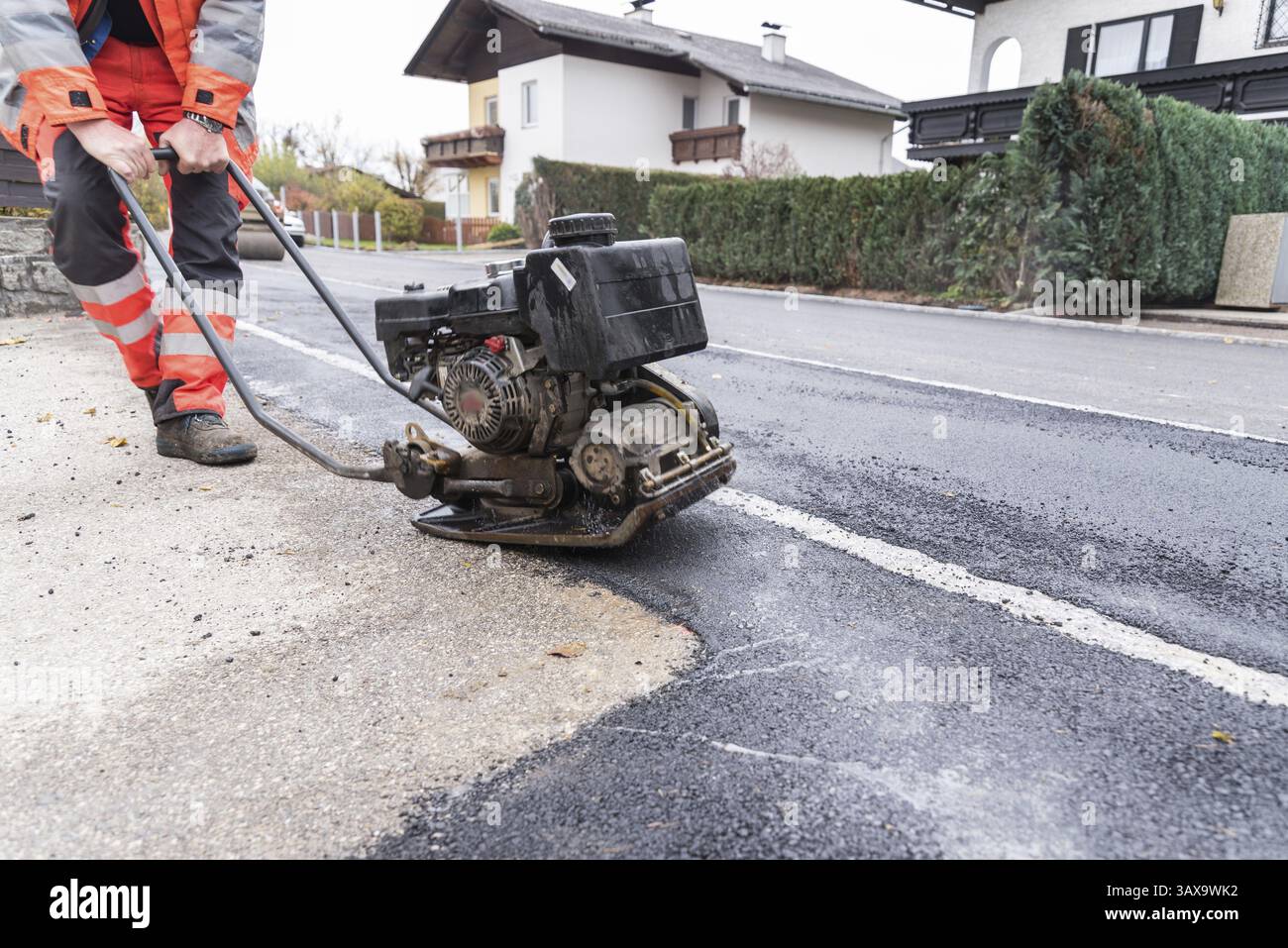 Operaio pesante che lavora su asfalto con un vibratore - primo piano Foto Stock