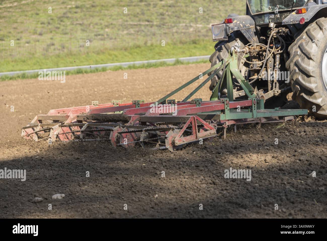 Coltivazione di un campo con un trattore e un erpice - primo piano di coltivazioni di seminativi Foto Stock