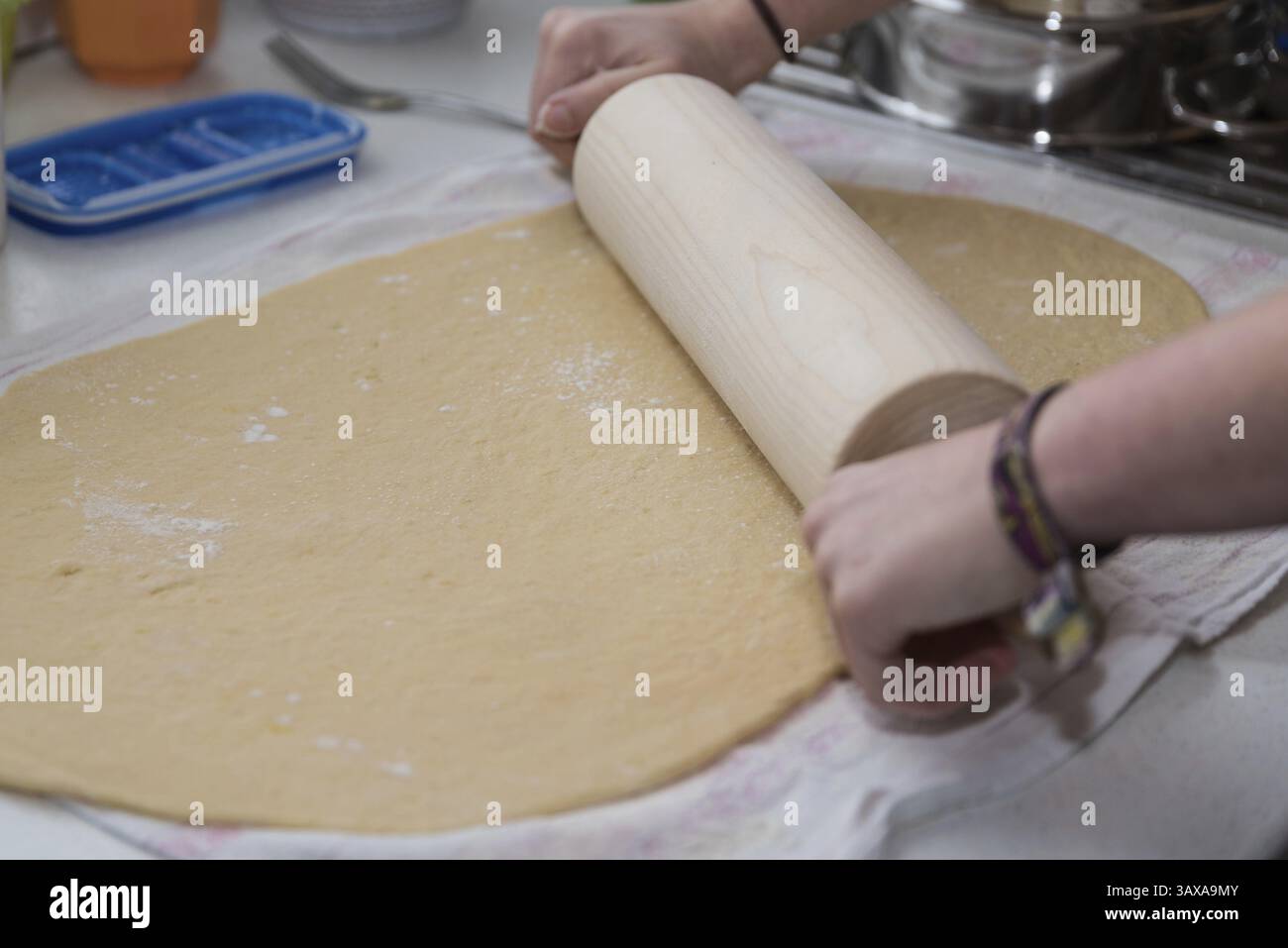 Cuocere l'impasto con un mattarello su un tavolo di lavoro, impastando in primo piano Foto Stock