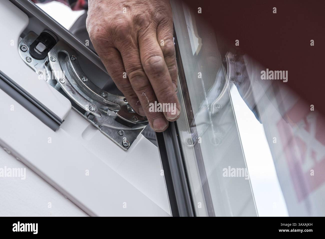 Idraulico del tetto che esegue gli interventi di manutenzione sul finestrino del tetto - primo piano del commerciante Foto Stock