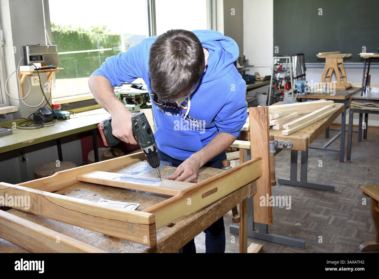 Carpenter inserisce qualcosa nel legno con un avvitatore a batteria - artigiano Foto Stock