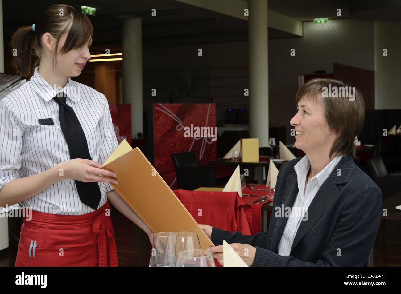Un giovane specialista di ristoranti presenta il menu agli ospiti Foto Stock