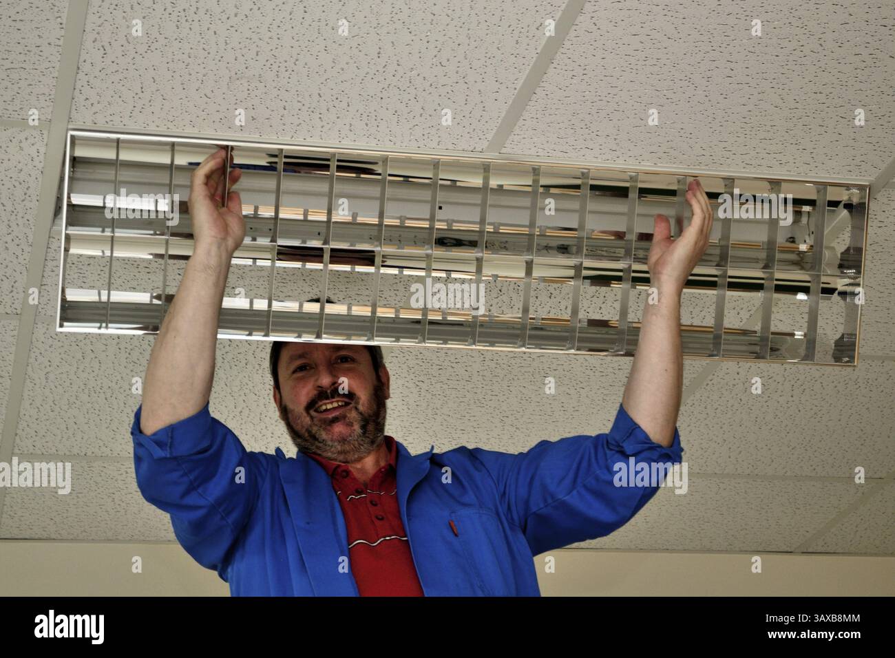 Il custode della scuola sostituisce la lampada rotta Foto Stock