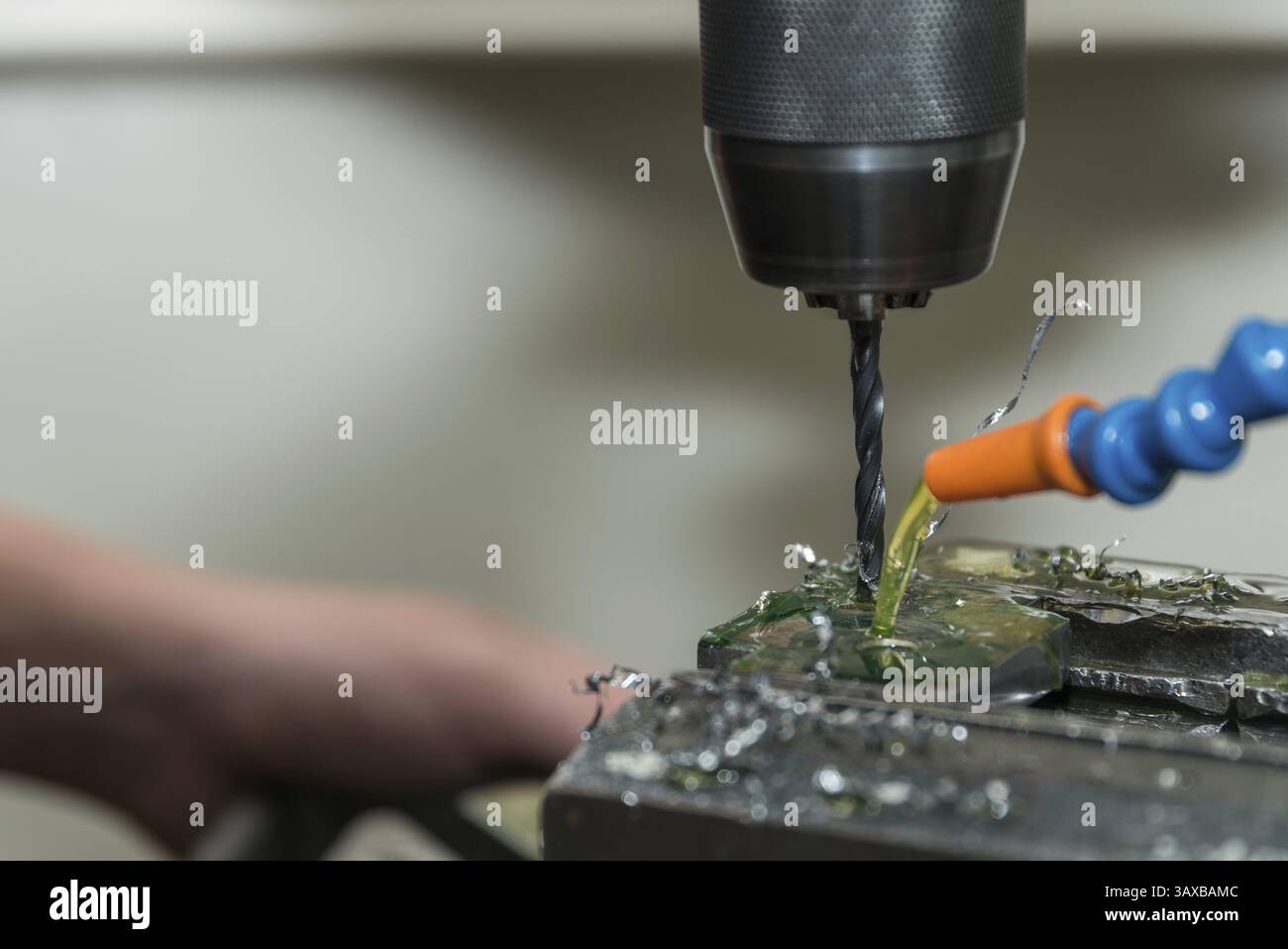 Praticare fori in plastica con un trapano e un liquido di raffreddamento - primo piano Foto Stock