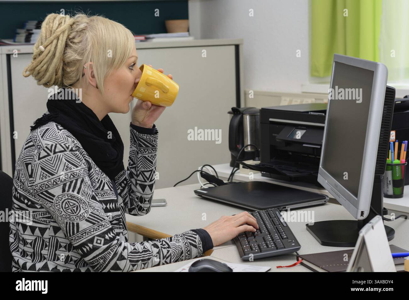 Un giovane impiegato d'ufficio beve caffè nel mezzo Foto Stock