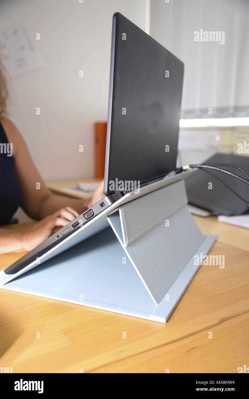 Il lavoratore in ufficio lavora su un computer portatile con dispositivo di fissaggio, un luogo di lavoro ergonomico Foto Stock