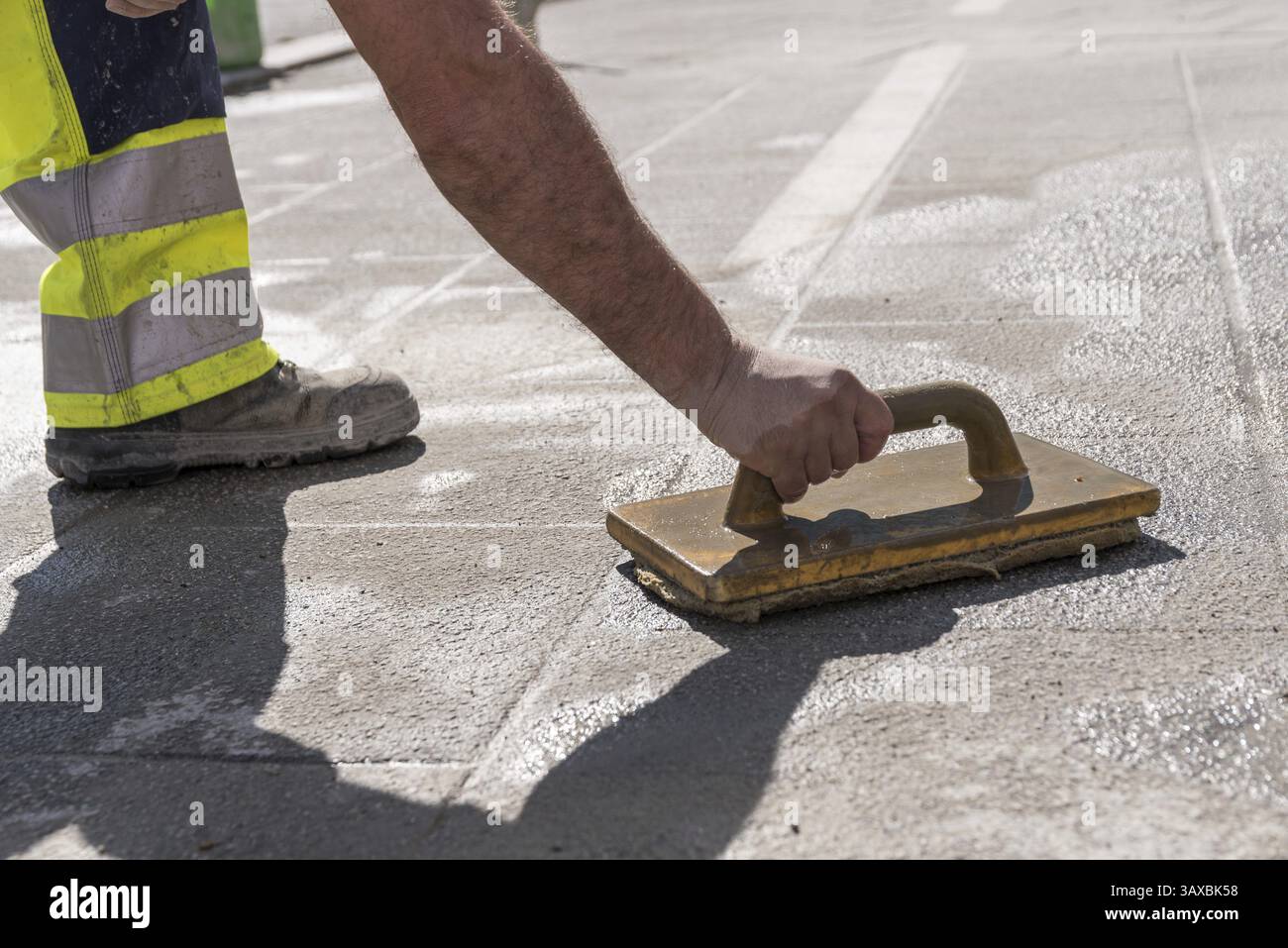 Lavoratore stradale con attrezzature per piastrelle al lavoro - primo piano Foto Stock