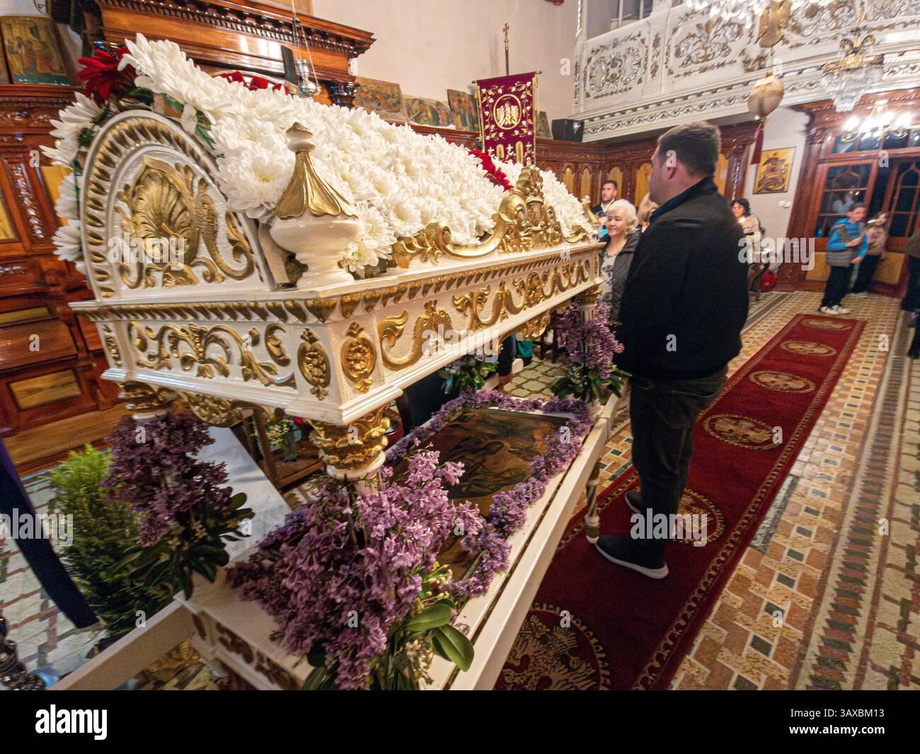 corfù, corfù, Grecia. 18 aprile 2025: Epitaphios adornato con fiori bianchi e lilla viola durante la celebrazione pasquale ortodossa. Foto Stock