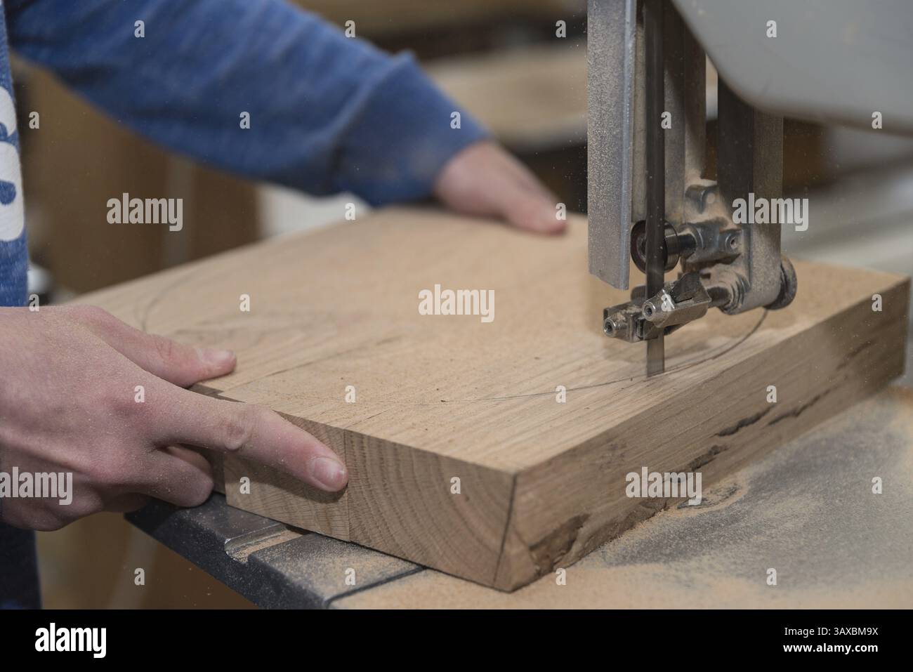 Falegname che taglia un pezzo di legno con una sega a nastro da tavolo - primo piano Foto Stock