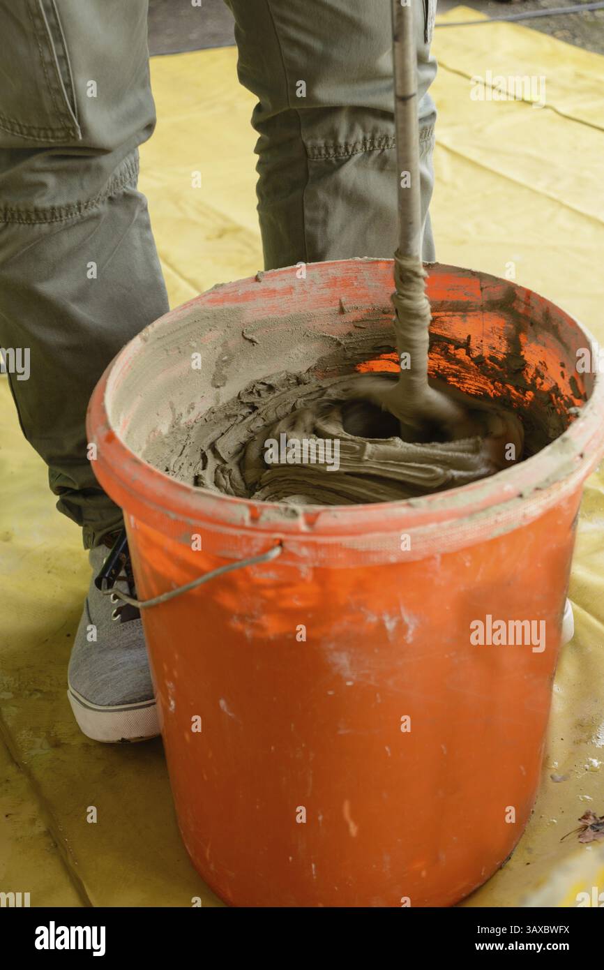 L'operatore mescola l'adesivo per piastrelle nel secchio Foto Stock