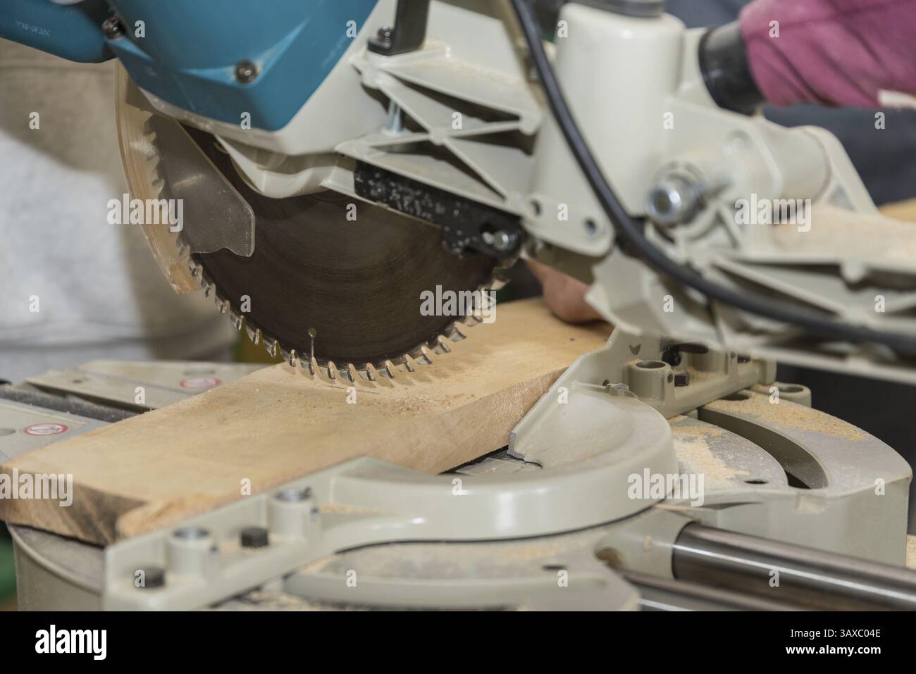 Falegname che taglia un pezzo di legno in un'officina con una sega - troncatrice Foto Stock