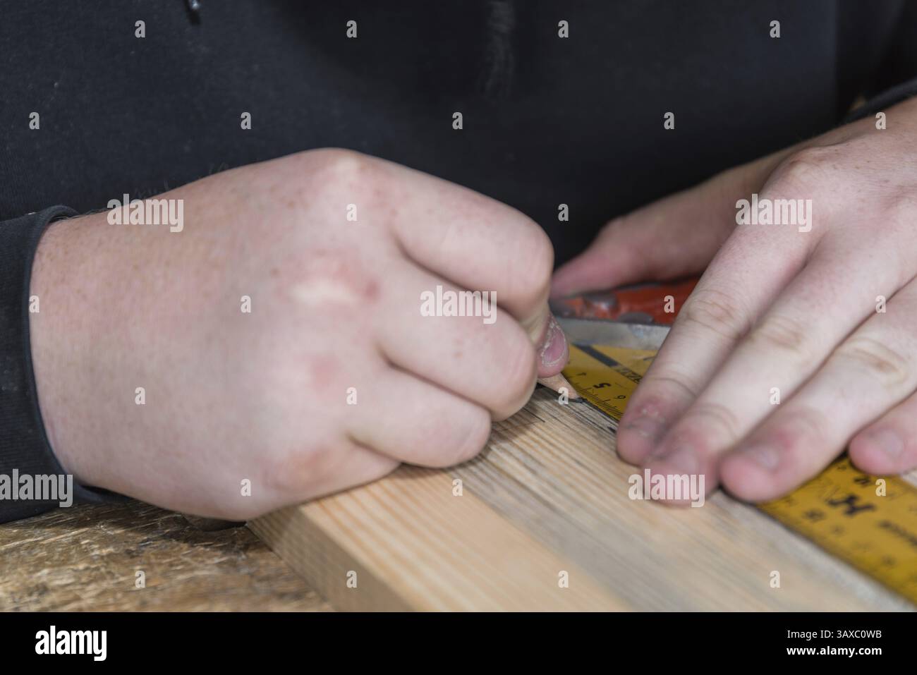 Carpenter misura il legno con un righello angolare e contrassegna le interfacce - primo piano della stazione di lavoro del carpentiere Foto Stock