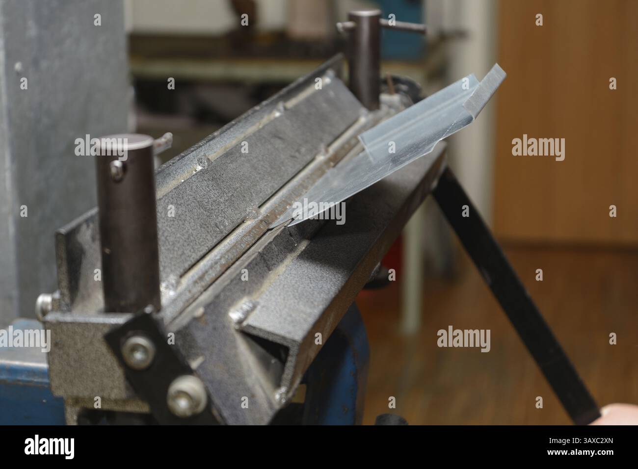 L'artigiano lavora la lamiera con una macchina piegatrice Foto Stock