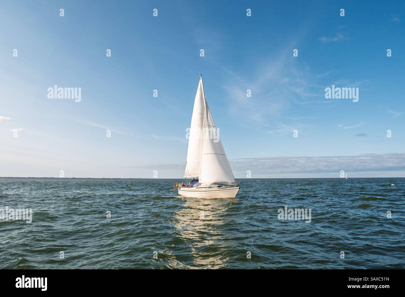 Crociera in barca a vela in mare aperto nel Mare di Wadden, bassa Sassonia, Germania, vele bianche sotto il cielo blu, attività di svago nel sito patrimonio dell'umanità dell'UNESCO Foto Stock