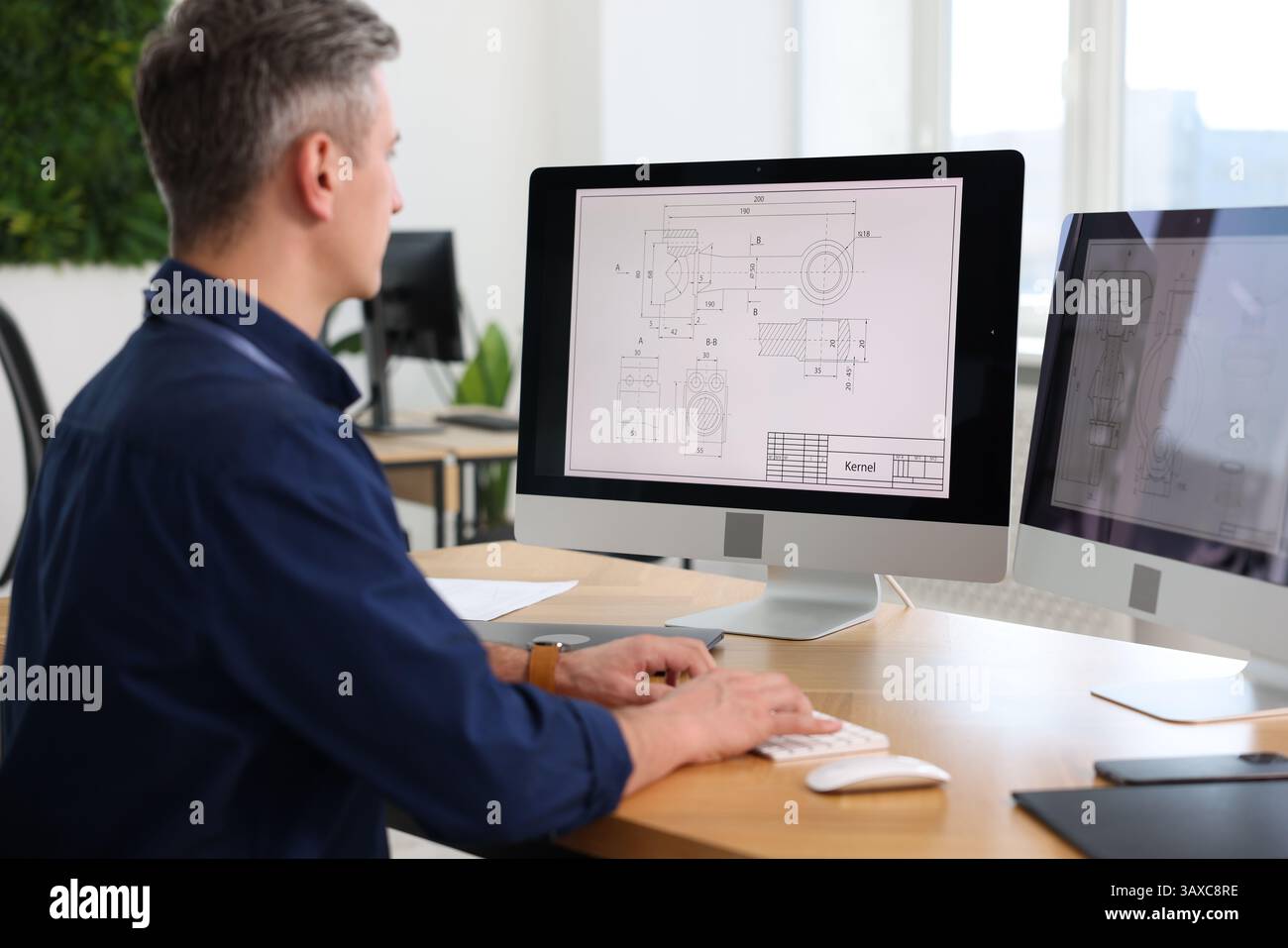 Ingegnere che lavora con disegni digitali al tavolo in ufficio Foto Stock