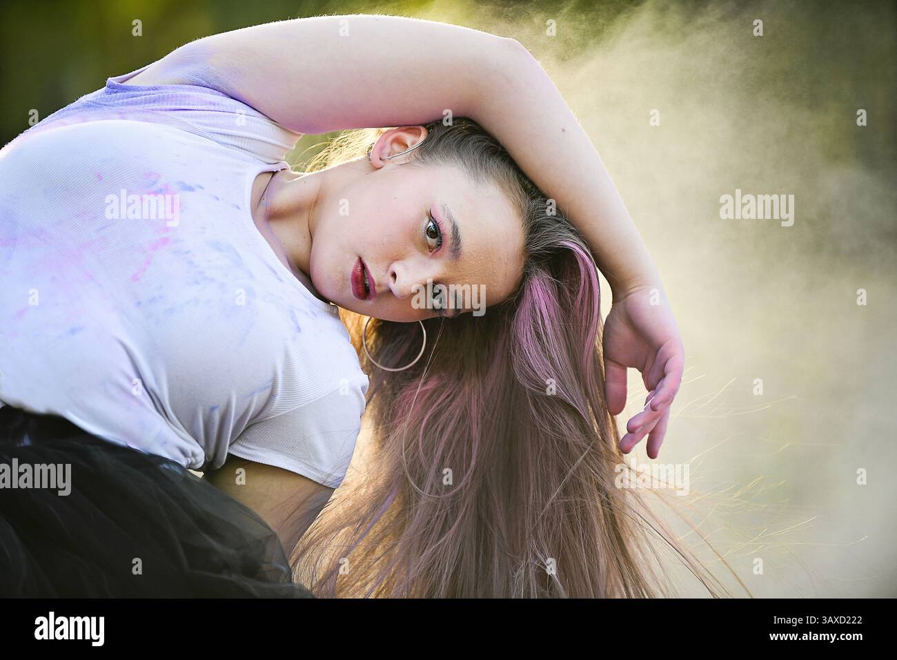 Donna in posa drammatica con capelli lunghi e polvere pastello in aria. Foto Stock Donna in posa drammatica con capelli lunghi e polvere pastello in aria. Foto Stock