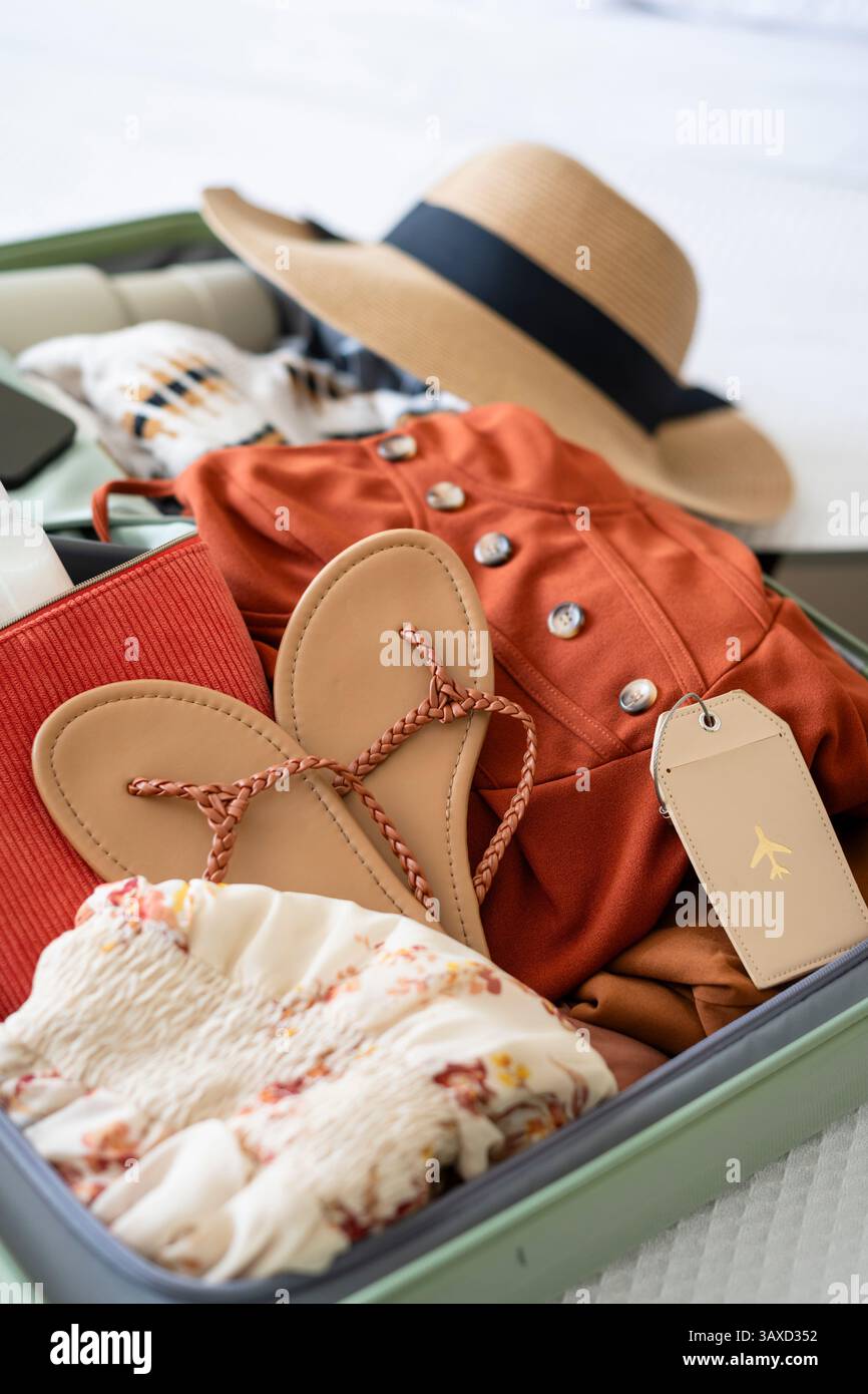 Primo piano della valigia con sandali, cappello e abbigliamento floreale Foto Stock