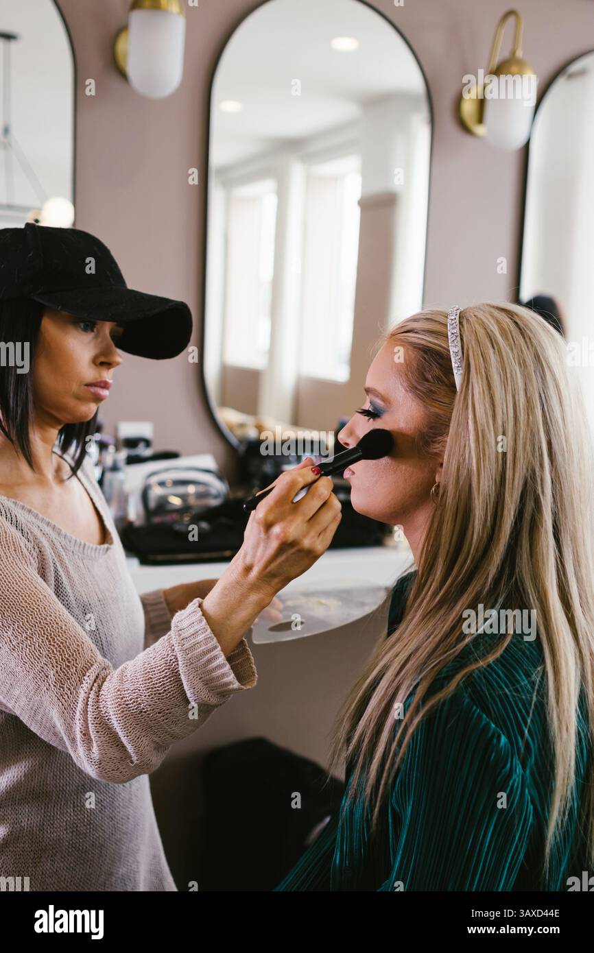 Cosmetologo pennello arrossisce la donna bionda nel salone Foto Stock