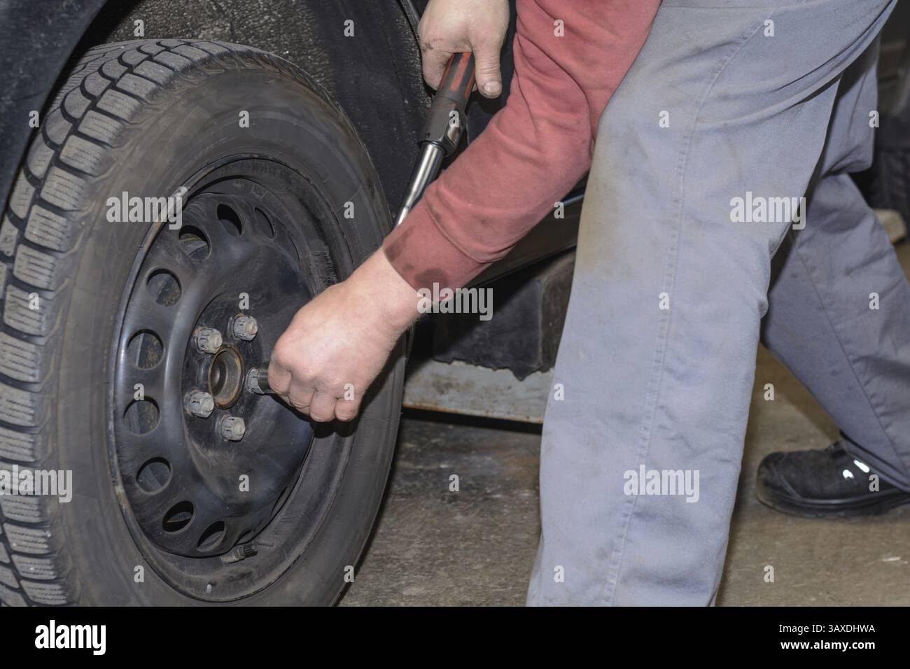 Lavoratore esperto con chiave dinamometrica quando si sostituiscono gli pneumatici Foto Stock