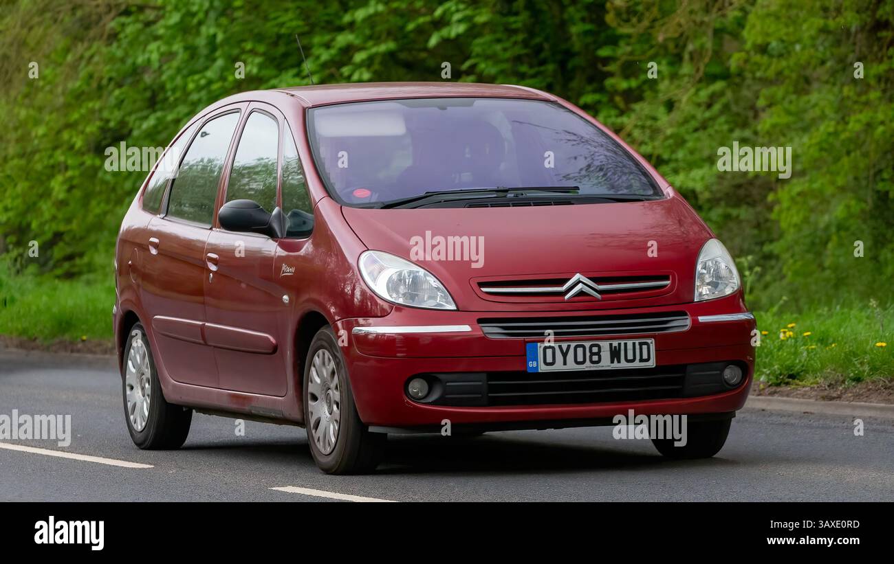Milton Keynes, Regno Unito - 9 aprile 2025: 2008 auto Citroen Xsara Picasso rossa che guida su una strada di campagna britannica Foto Stock