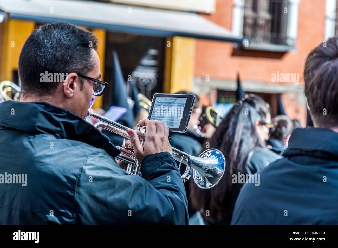 Processione del venerdì Santo EN el Calvario a Cuenca. Un giovane suona la tuba nel mezzo di un gruppo musicale spagnolo e ha le note sul suo kindle. Plaza Mayor, Cuenca, Castiglia-la Mancha, Spagna Foto Stock