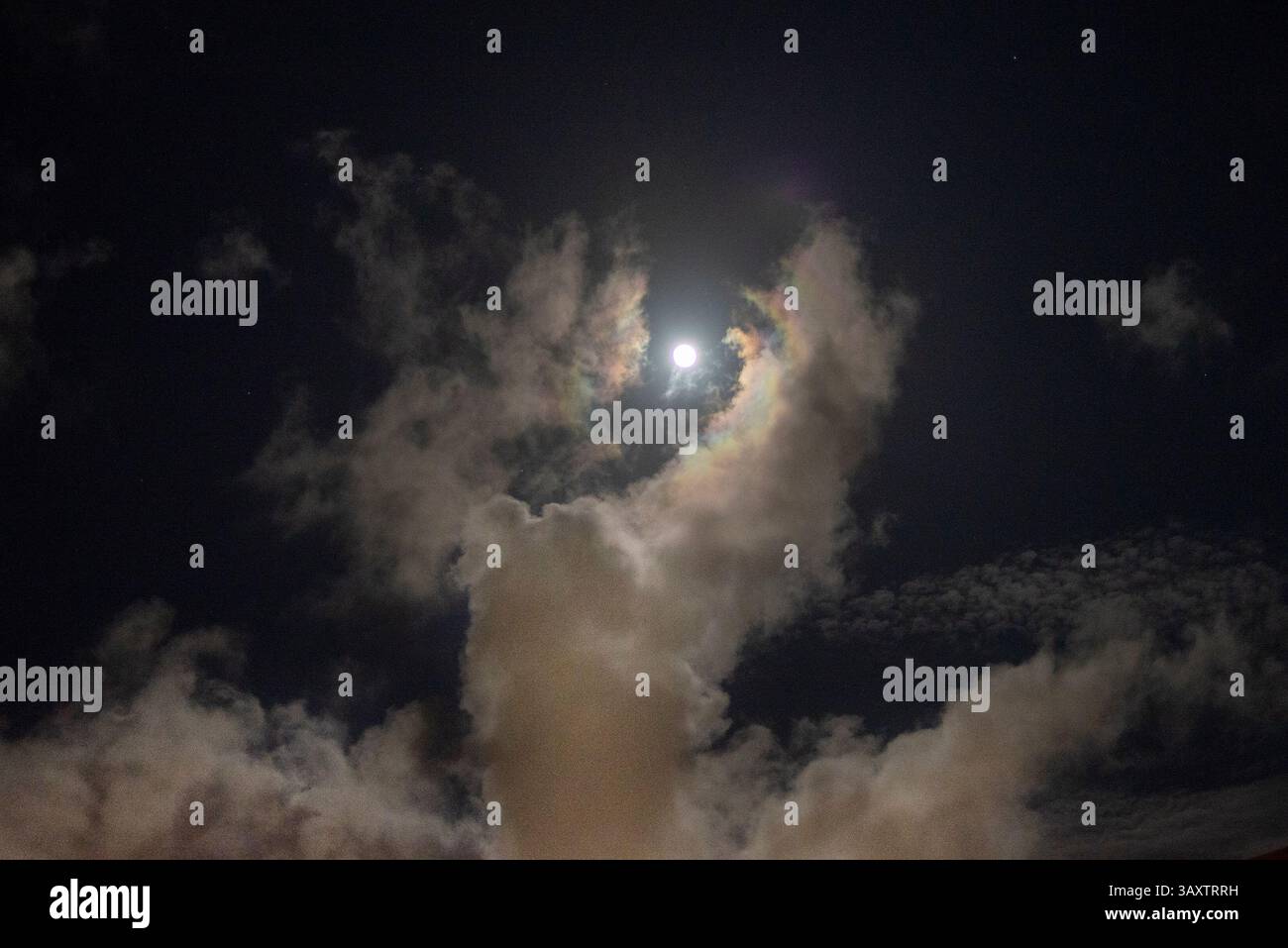 Durante una notte di luna piena a la Jolla, California, una collezione di nuvole a forma di gigante essere celeste sembrano avvolgere e sollevare la luna. Foto Stock