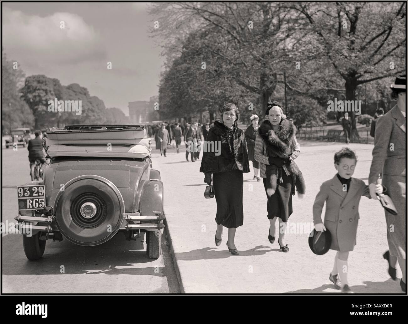 Champs Elysées vintage Paris 1936 con eleganti signore alla moda e bambini che gironzolano al sole (con accessori in pelliccia non PC). Stile di vita alla moda degli anni '1930 Arc de Triomphe in background. Fotografo Van de poll Parigi Francia Foto Stock
