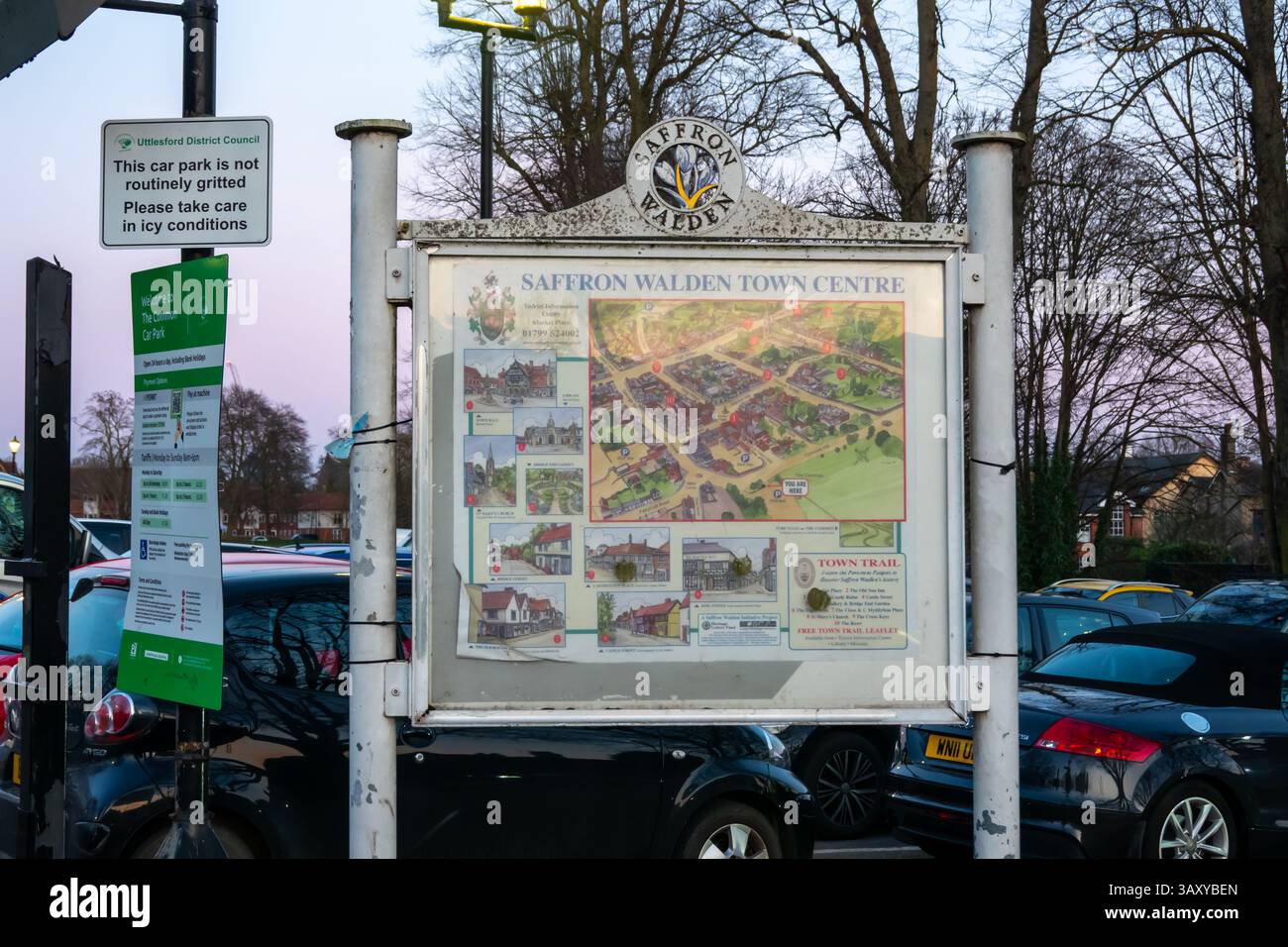 Un cartello che mostra una mappa del centro di Saffron Walden con altri cartelli e auto parcheggiate nelle vicinanze, girato nel Regno Unito. Foto Stock