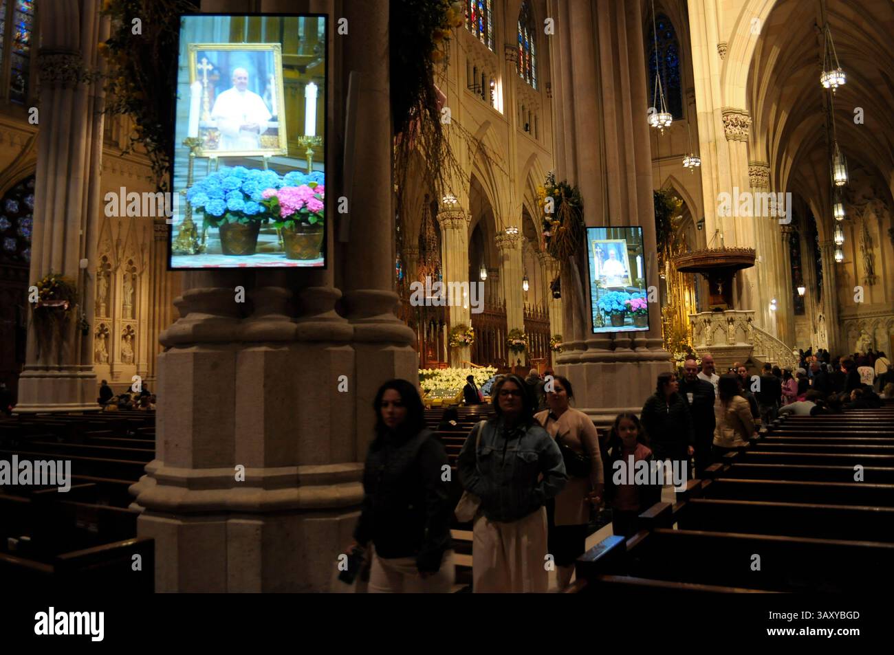 New York, Stati Uniti. 21 aprile 2025. Foto di Papa Francesco viste sugli schermi televisivi della Cattedrale di San Patrizio. La cattedrale di San Patrizio ha tenuto una funzione commemorativa per Papa Francesco, morto lunedì 21 aprile all'età di 88 anni. I fedeli si riunirono nella cattedrale per rendere omaggio al defunto papa. La domenica di Pasqua, Papa Francesco ha salutato migliaia di fedeli in Piazza San Pietro. Il Vaticano ha detto che il papa è morto per un ictus che ha portato a coma e insufficienza cardiaca. Credito: SOPA Images Limited/Alamy Live News Foto Stock