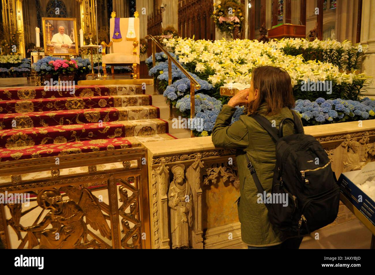 New York, Stati Uniti. 21 aprile 2025. Una persona prega di fronte a una foto di Papa Francesco nella cattedrale di San Patrizio. La cattedrale di San Patrizio ha tenuto una funzione commemorativa per Papa Francesco, morto lunedì 21 aprile all'età di 88 anni. I fedeli si riunirono nella cattedrale per rendere omaggio al defunto papa. La domenica di Pasqua, Papa Francesco ha salutato migliaia di fedeli in Piazza San Pietro. Il Vaticano ha detto che il papa è morto per un ictus che ha portato a coma e insufficienza cardiaca. Credito: SOPA Images Limited/Alamy Live News Foto Stock