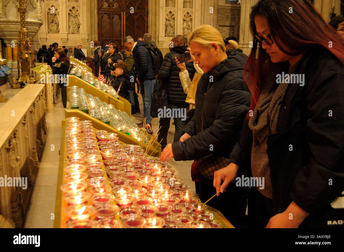 New York, Stati Uniti. 21 aprile 2025. La gente accende le candele nella cattedrale di San Patrizio. La cattedrale di San Patrizio ha tenuto una funzione commemorativa per Papa Francesco, morto lunedì 21 aprile all'età di 88 anni. I fedeli si riunirono nella cattedrale per rendere omaggio al defunto papa. La domenica di Pasqua, Papa Francesco ha salutato migliaia di fedeli in Piazza San Pietro. Il Vaticano ha detto che il papa è morto per un ictus che ha portato a coma e insufficienza cardiaca. Credito: SOPA Images Limited/Alamy Live News Foto Stock