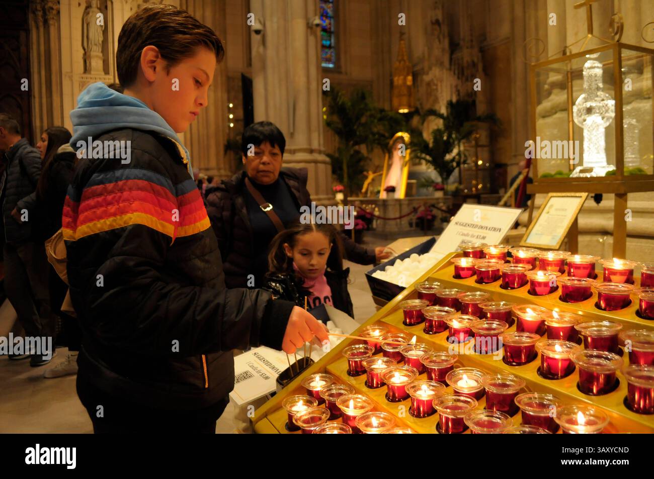 New York, Stati Uniti. 21 aprile 2025. Una persona accende una candela nella cattedrale di San Patrizio. La cattedrale di San Patrizio ha tenuto una funzione commemorativa per Papa Francesco, morto lunedì 21 aprile all'età di 88 anni. I fedeli si riunirono nella cattedrale per rendere omaggio al defunto papa. La domenica di Pasqua, Papa Francesco ha salutato migliaia di fedeli in Piazza San Pietro. Il Vaticano ha detto che il papa è morto per un ictus che ha portato a coma e insufficienza cardiaca. (Foto di Jimin Kim/SOPA Images/Sipa USA) credito: SIPA USA/Alamy Live News Foto Stock