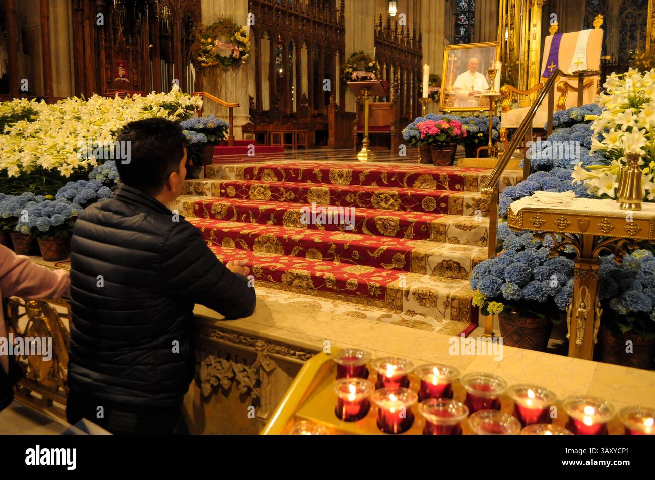 New York, Stati Uniti. 21 aprile 2025. Una persona prega di fronte a una foto di Papa Francesco nella cattedrale di San Patrizio. La cattedrale di San Patrizio ha tenuto una funzione commemorativa per Papa Francesco, morto lunedì 21 aprile all'età di 88 anni. I fedeli si riunirono nella cattedrale per rendere omaggio al defunto papa. La domenica di Pasqua, Papa Francesco ha salutato migliaia di fedeli in Piazza San Pietro. Il Vaticano ha detto che il papa è morto per un ictus che ha portato a coma e insufficienza cardiaca. (Foto di Jimin Kim/SOPA Images/Sipa USA) credito: SIPA USA/Alamy Live News Foto Stock