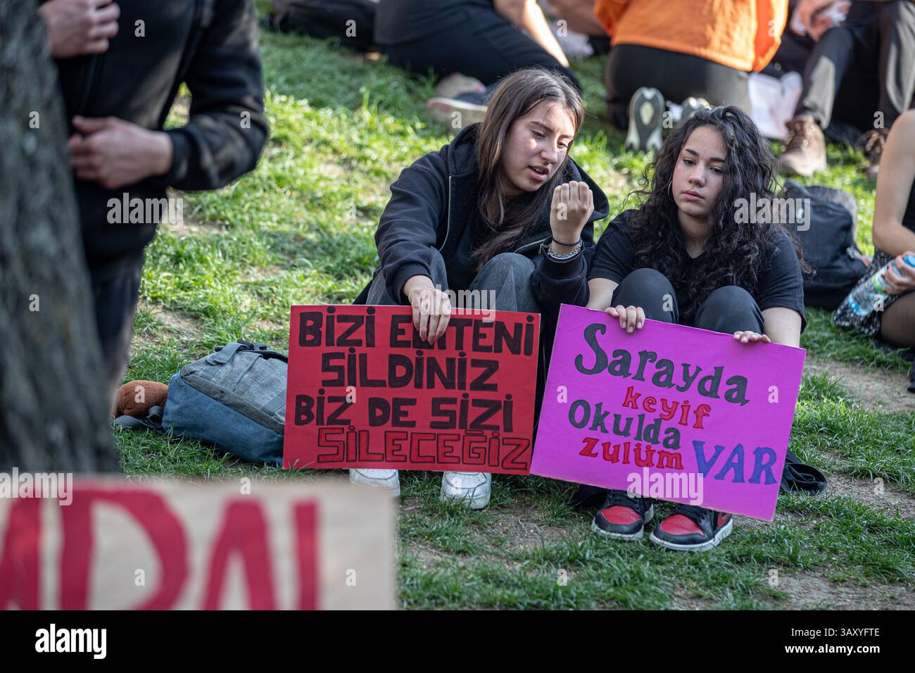 Ankara, Turchia. 21 aprile 2025. Due studenti delle scuole superiori si siedono con i loro cartelli durante la protesta. Gli studenti delle scuole superiori si sono riuniti al Parco Ku'ulu per protestare contro il processo politico iniziato con l'arresto del sindaco del comune metropolitano di Istanbul Ekrem 'mamo'lu. (Foto di Tunahan Turhan/SOPA Images/Sipa USA) credito: SIPA USA/Alamy Live News Foto Stock