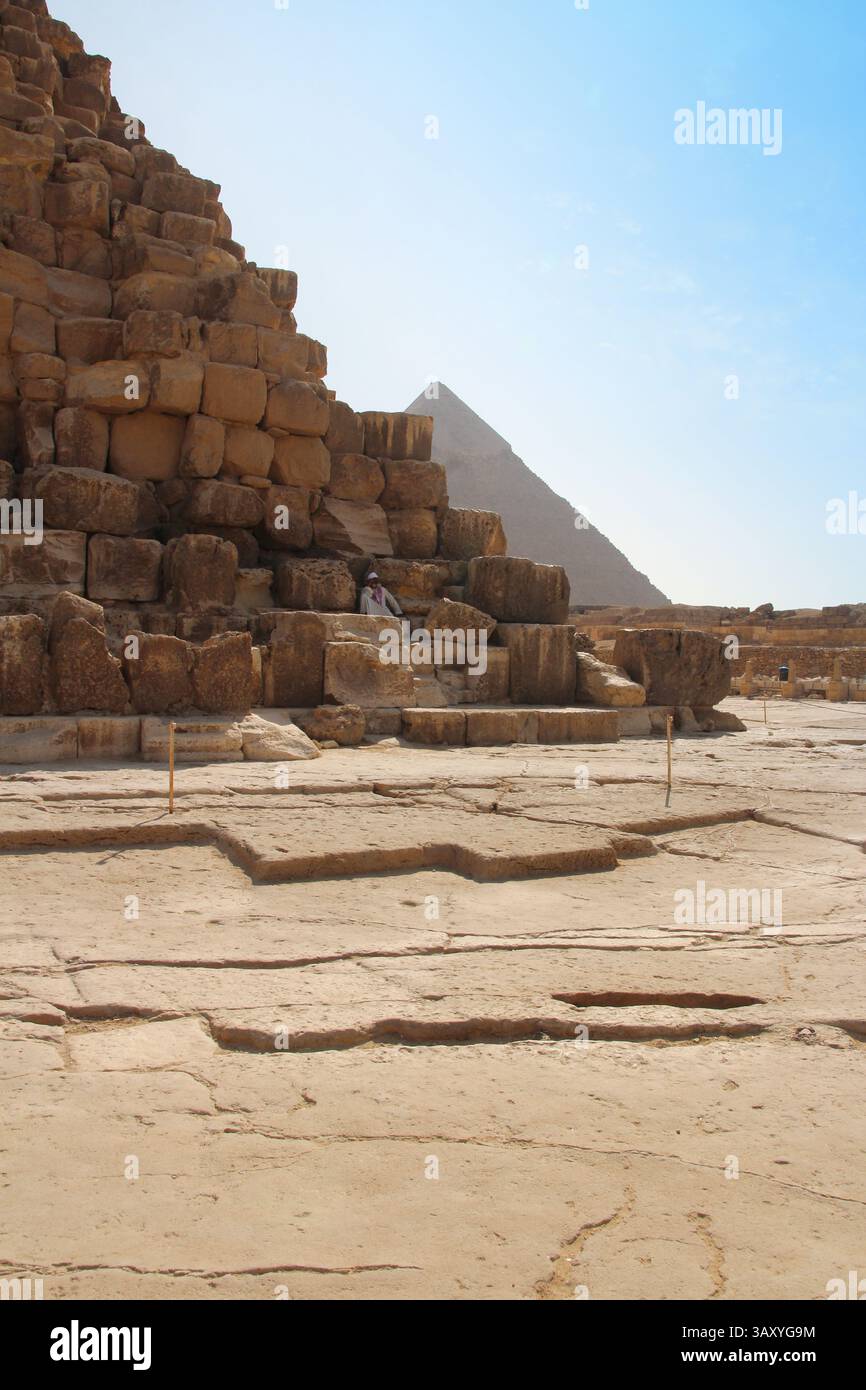 Giza, Egitto - 19 ottobre 2023: Un vecchio egiziano seduto su un blocco delle piramidi di Khufu Foto Stock