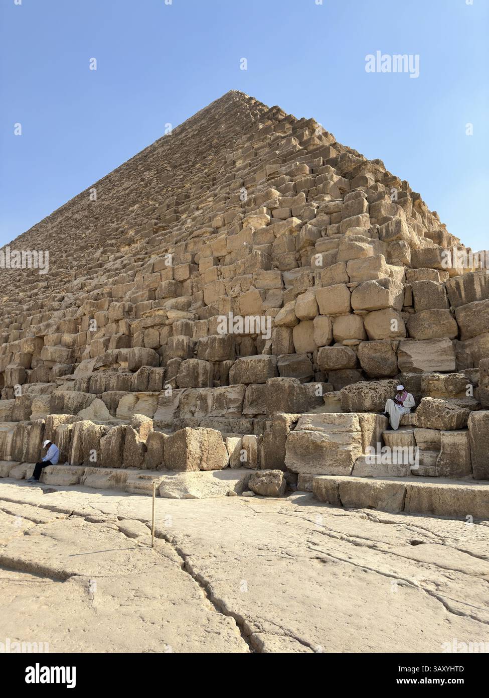 Giza, Egitto - 19 ottobre 2023: Un vecchio egiziano seduto su un blocco delle piramidi di Khufu Foto Stock