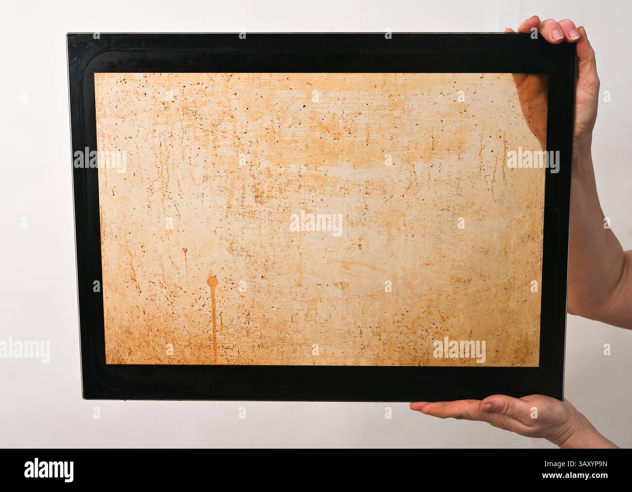 il vetro interno del forno è sporco di grasso. Tra le mani su uno sfondo bianco Foto Stock