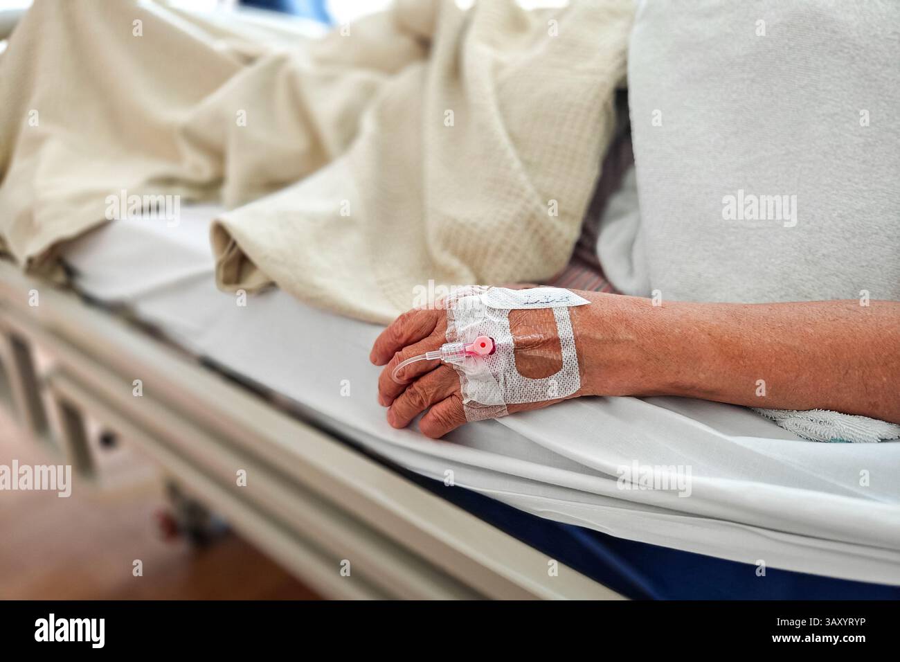 Paziente sdraiato nel letto d'ospedale. Primo piano a portata di mano con flebo IV. Foto Stock