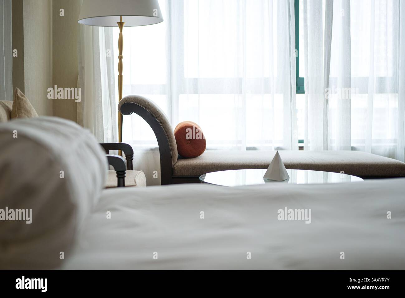 Camera d'hotel con finestre. Vista sul divano e sul letto con coperta bianca. Foto Stock