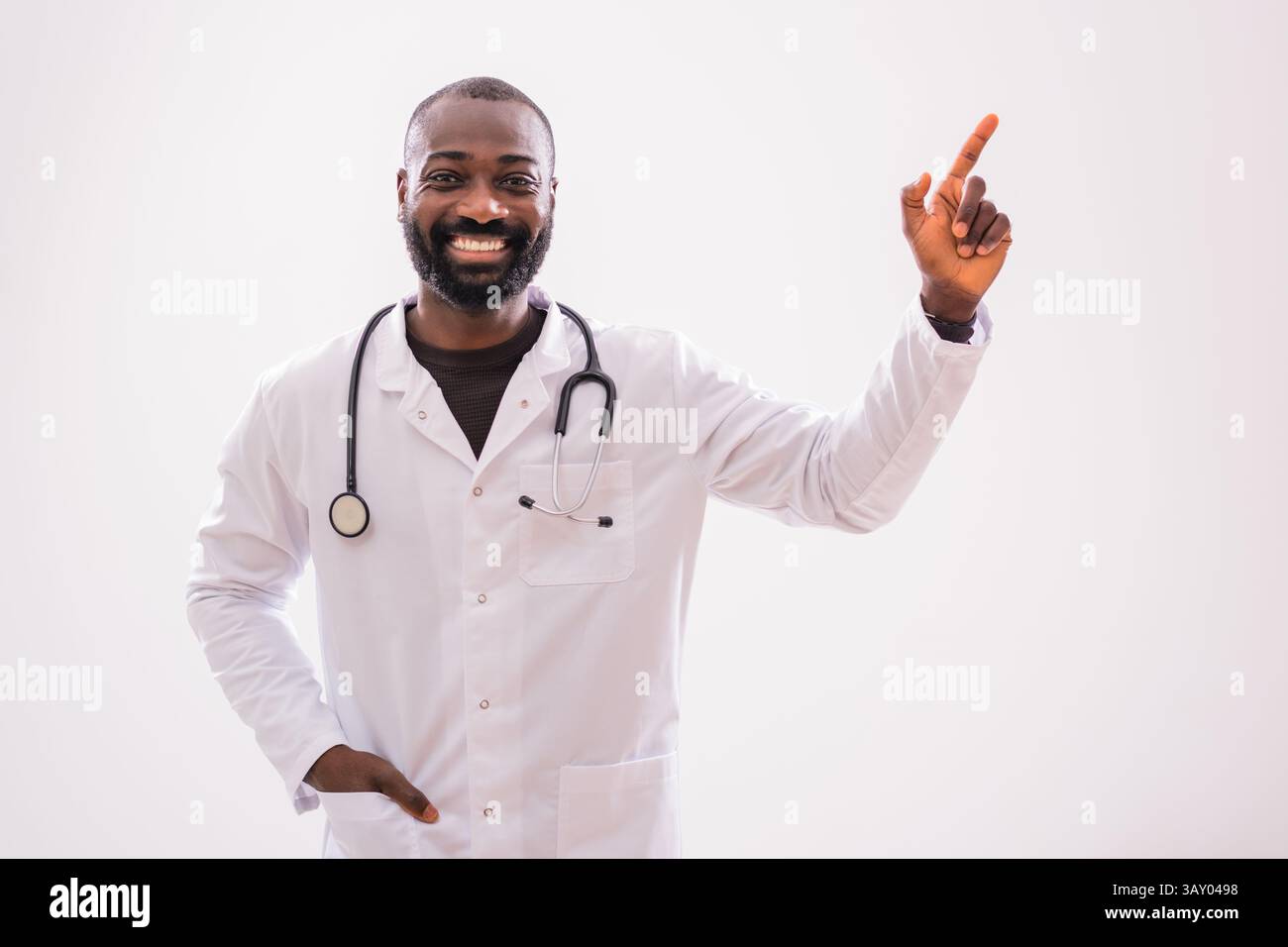 Ritratto di un medico afroamericano che punta verso l'alto con un sorriso allegro. Copia spazio per il testo o l'annuncio. Foto Stock
