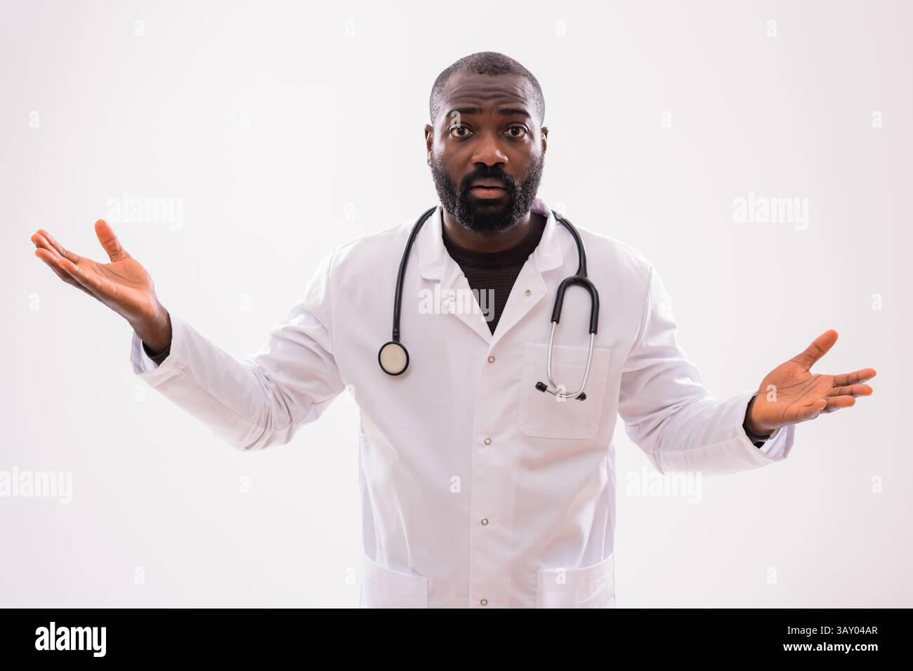 Ritratto di serio nero operatore sanitario maschile con gesti di espressione preoccupati e confusi su sfondo grigio. Foto Stock