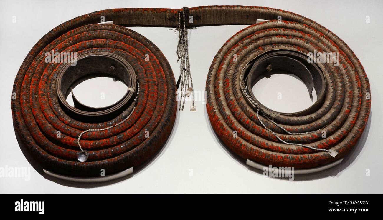 Tevau, chiamato anche "denaro piuma". Consisteva in una striscia di fibra vegetale larga circa 7 cm e lunga 10 m., a forma di ruota filettata su due anelli di corteccia d'albero, tessuta su un lato con file di piccole piume rosse sovrapposte, di un uccello mangiatore di miele chiamato Cardinale Myzomela. La sua fabbricazione era molto complessa e fu tramandata di padre in figlio, poiché le sue componenti magiche non erano alla portata di tutti. Questi rotoli di piume sono stati utilizzati come denaro per pagamenti rituali, come la cerimonia del matrimonio, e per acquistare beni di alto valore. Sono stati accuratamente conservati in luoghi asciutti e caldi a preserv Foto Stock