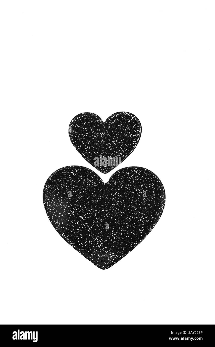 Due simboli di cuore nero scintillante uno piccolo grande che giace l'uno sopra l'altro Foto Stock