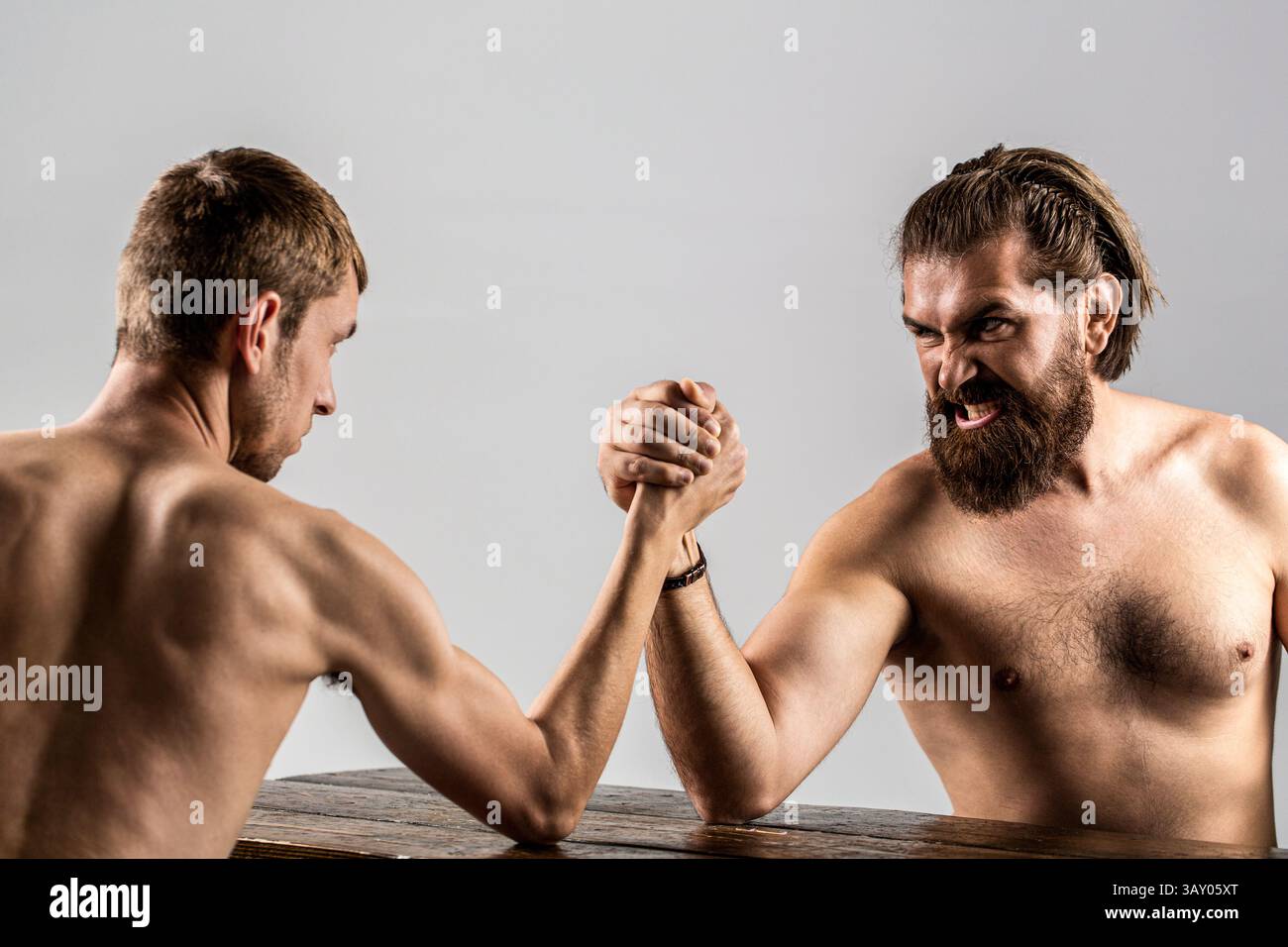 Primo piano di un uomo muscoloso che gioca a braccio lottando con uno magro. Lotta al braccio. Le mani di due uomini stringevano il braccio, forti e deboli, disuguali Foto Stock