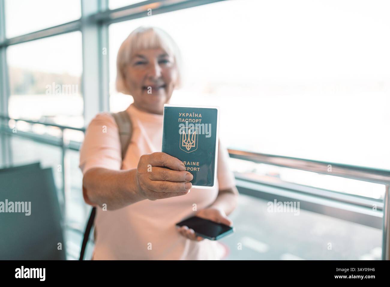 Donna anziana con passaporto e smartphone al check-in in aeroporto Foto Stock