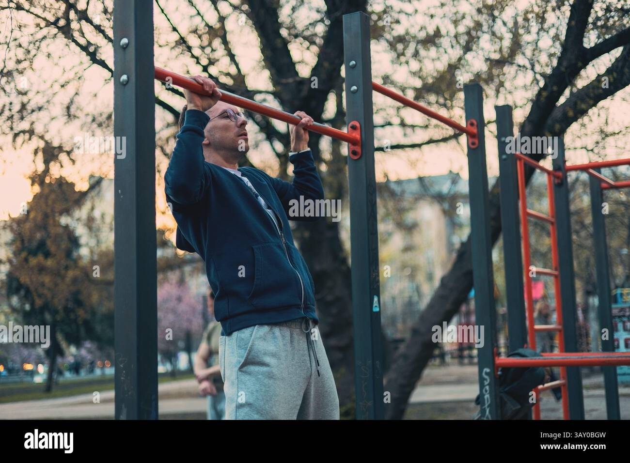 Un ragazzo fa pull-up su un terreno sportivo per mantenere una buona salute Foto Stock