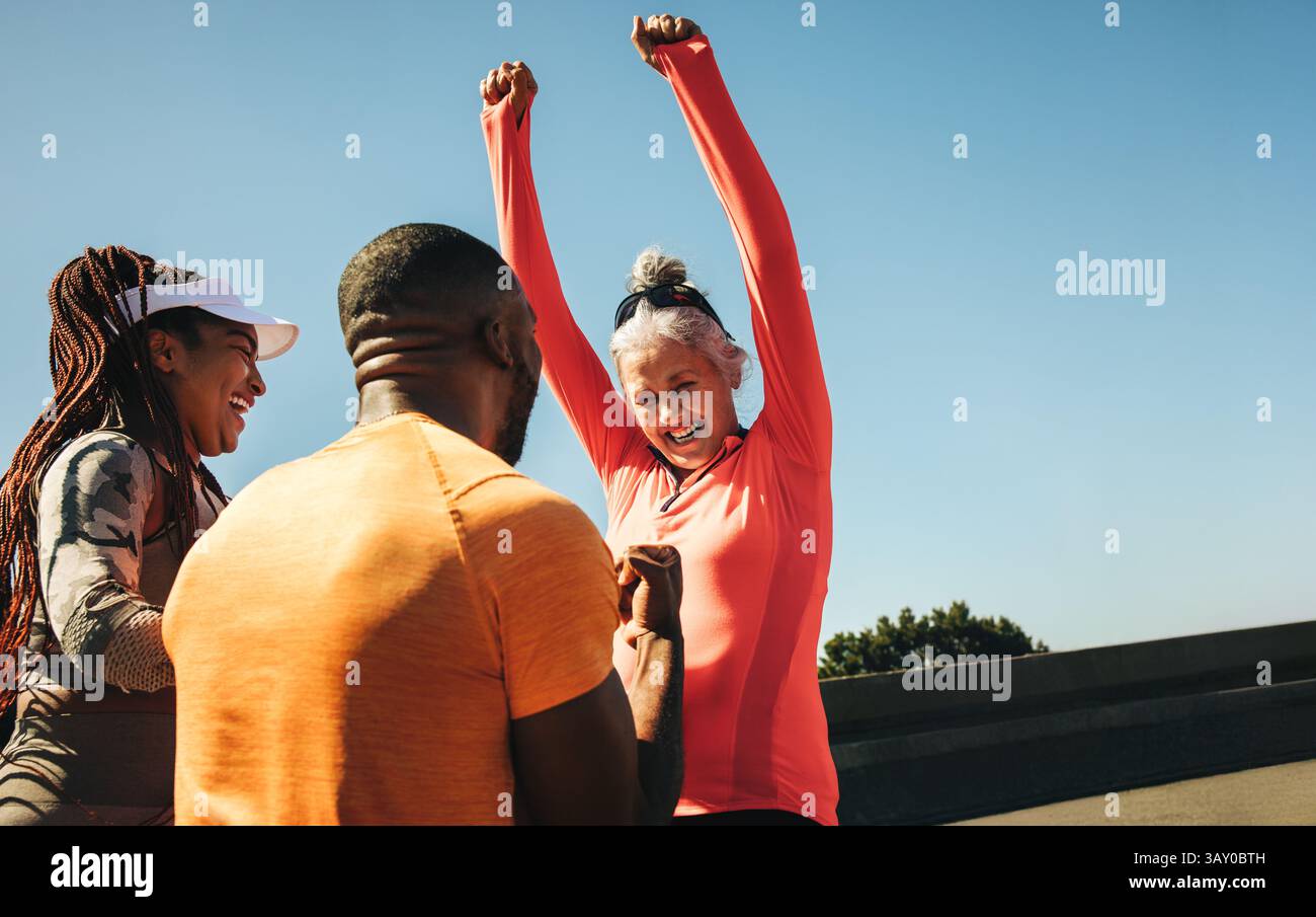 Un gruppo di amici esprime gioia e trionfo dopo aver completato con successo una corsa su strada. Sono entusiasti e festeggiano il loro successo per ottenere Foto Stock